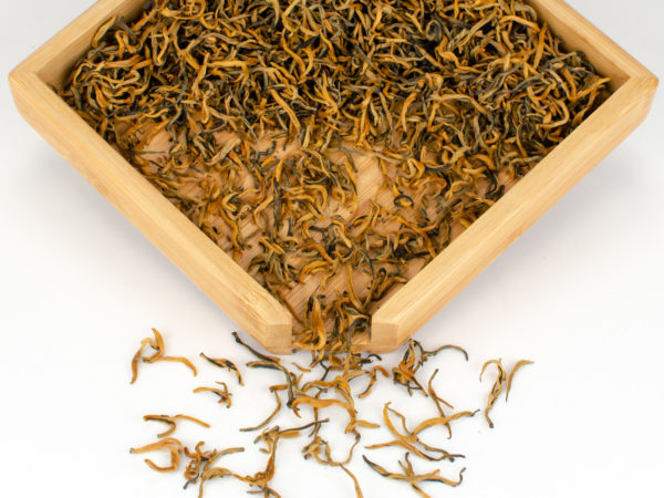 Jinya (Golden Buds) black tea dry leaves in a wooden display box.