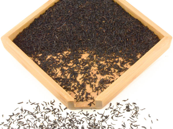 Premium Qimen black tea dry leaves in a wooden display box.