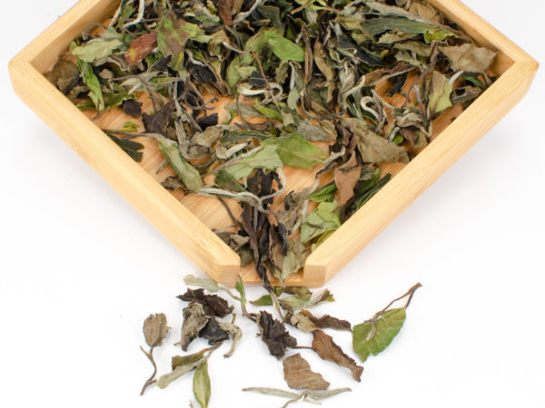 Bai Mudan (White Peony) dry white tea leaves displayed on a bamboo tray.