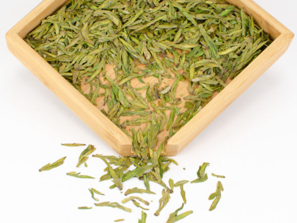 Da Fo Longjing (Big Buddha Dragon Well) dry green tea leaves displayed on a bamboo tray.