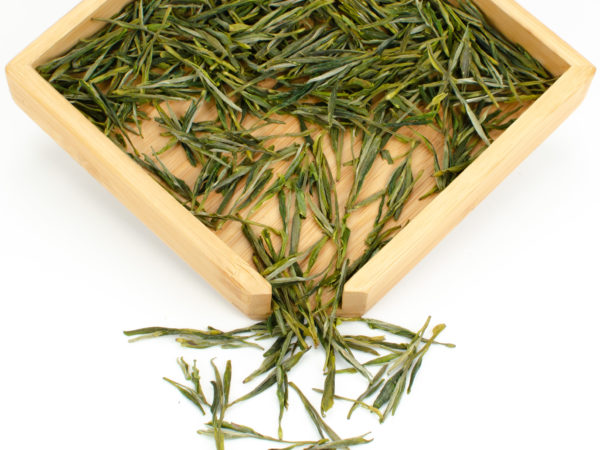 Guzhu Zisun (Purple Bamboo) dry green tea leaves displayed on a bamboo tray.
