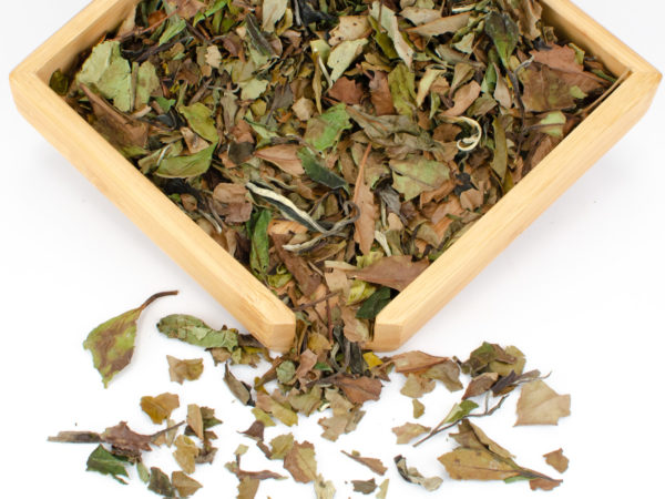 Shou Mei (Longevity Eyebrow) dry white tea leaves displayed on a bamboo tray.