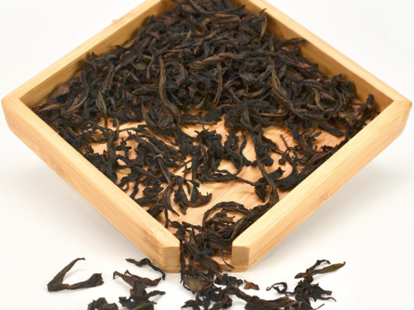 Handmade Rougui rock wulong tea dry leaves in a wooden display box.