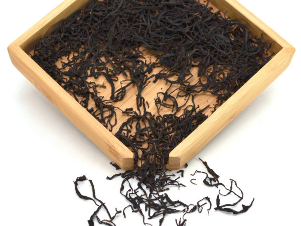 Late Harvest Qimen Caixia black tea dry leaves in a wooden display box.