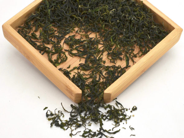Xianghao green tea dry leaves in a wooden display box.