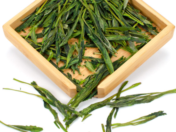 Tai Ping Houkui dry green tea leaves displayed on a bamboo tray.