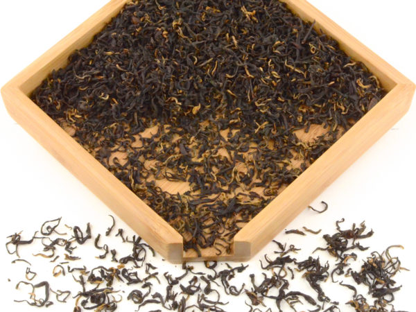 Golden Lapsang Souchong black tea dry leaves in a wooden display box.