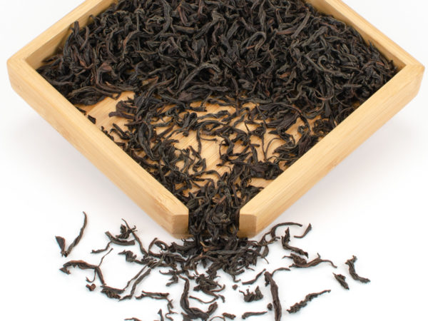 Chi Gan (Sweet Vermilion) dry black tea leaves displayed on a bamboo tray.