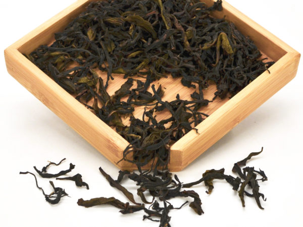 Traditional Tieguanyin Anxi wulong tea dry leaves in a wooden display box.