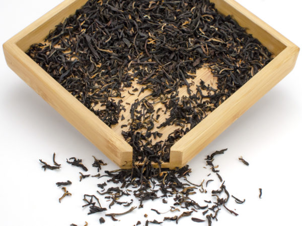 Premium Orthodox black tea dry leaves in a wooden display box.