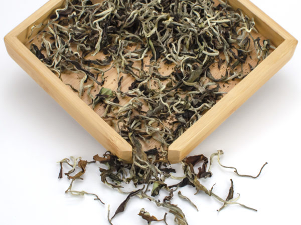 Premium White Tea dry leaves in a wooden display box.