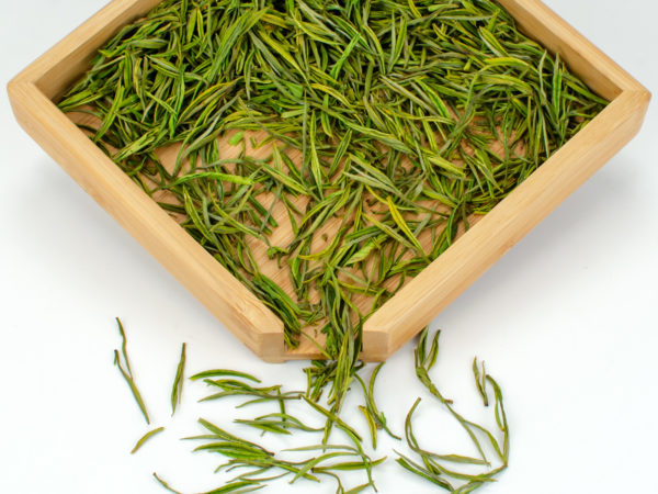 Ming Qian Anji Baicha (Early Harvest Anji) dry green tea leaves displayed on a bamboo tray.