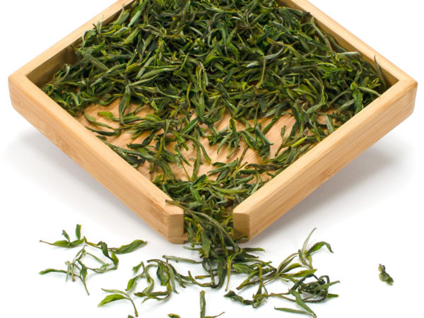 Mountain Forest Huangshan Maofeng dry green tea leaves displayed on a bamboo tray.