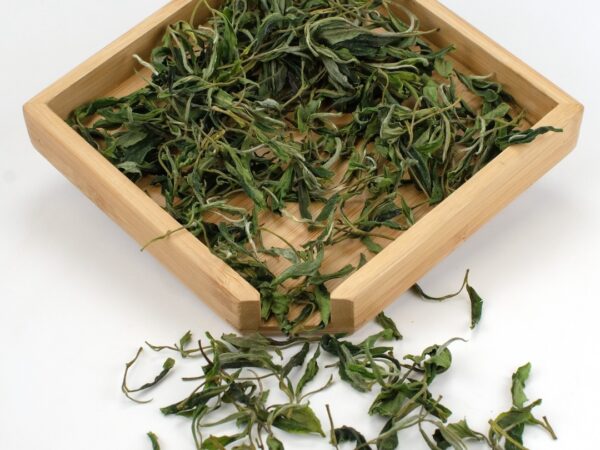 Mountain Forest Huangshan Maofeng dry green tea leaves displayed on a bamboo tray.