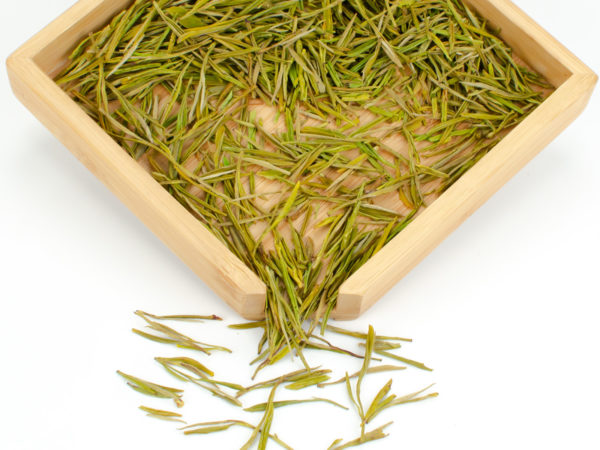 Huang Jin Ye (Golden Leaf) dry green tea leaves displayed on a bamboo tray.