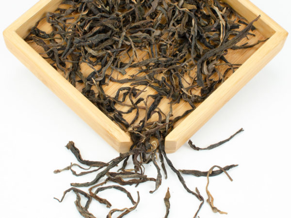 Laowushan (Laowu Mountain) sheng puer tea dry leaves in a wooden display box.
